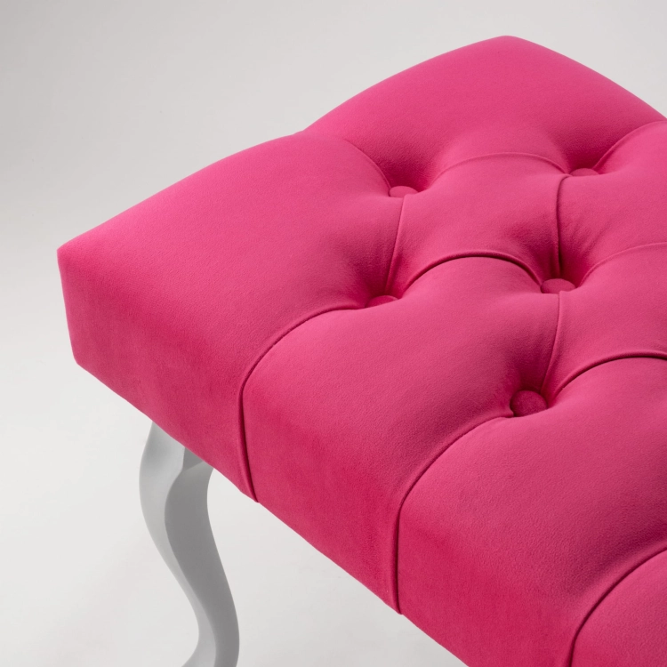 Stijlvolle gewatteerde fuchsia bank met zilverkleurige metalen poten, ideaal voor in de woonkamer of kleedkamer