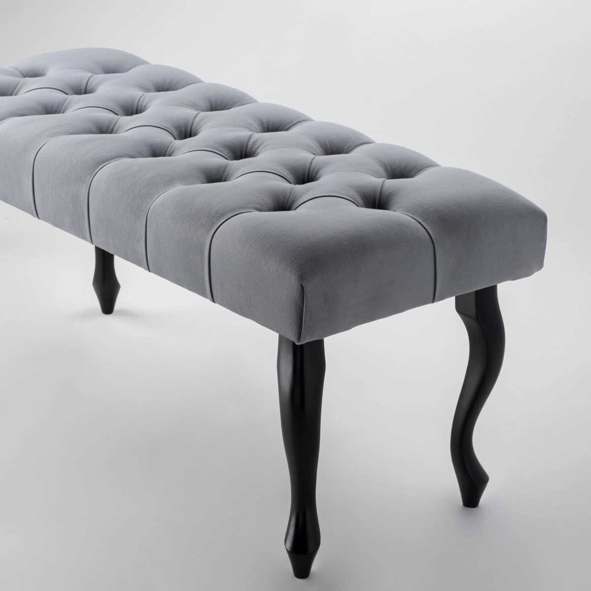 Bank in grijze tint met quilting en zwarte poten